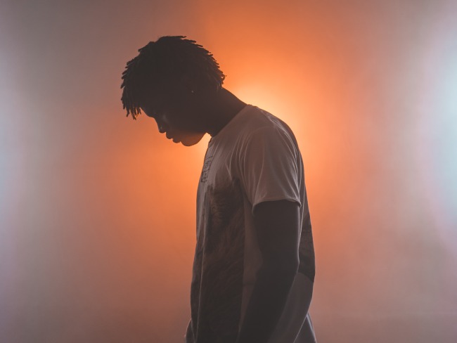 Young man standing in front of a glowing orange background