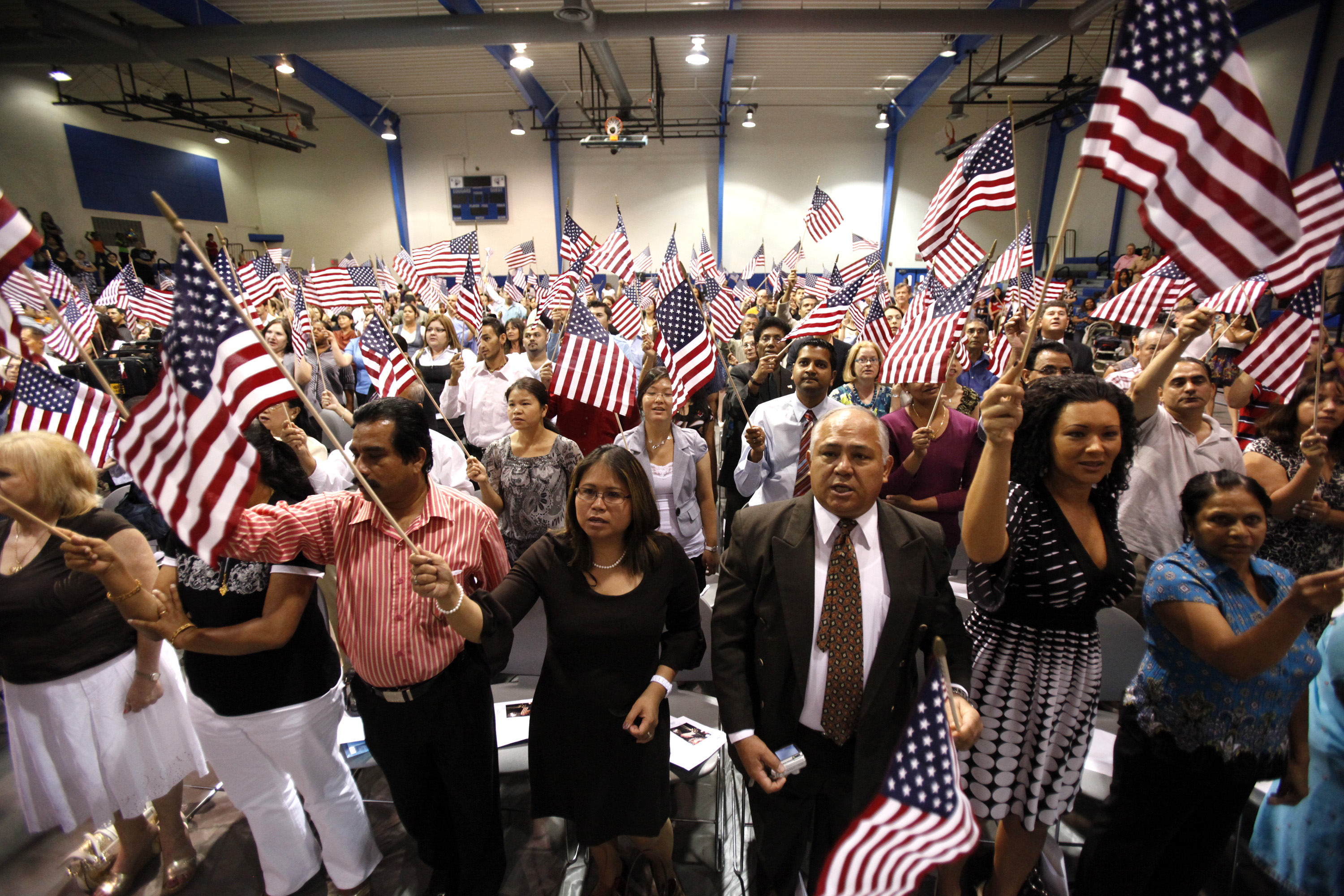 People hold flags as they are sworn in as U.S. citizens during a naturalization ceremony on Tuesday, July 2, 2010 in Phoenix. (AP Photo/Rick Scuteri)